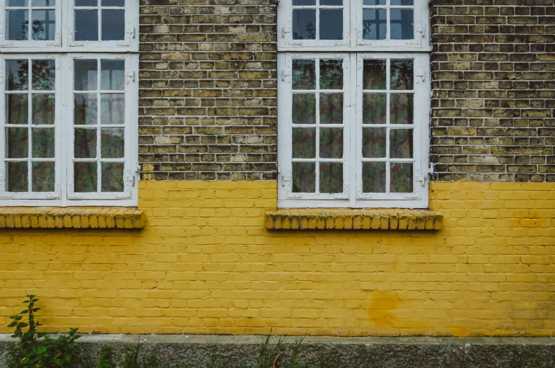 two windows in a yellow brick building with white trim