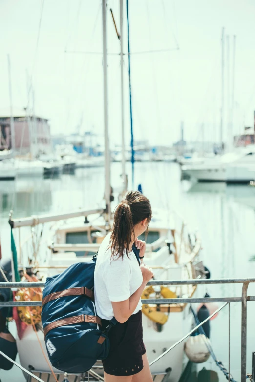 a girl standing at the pier using her cell phone