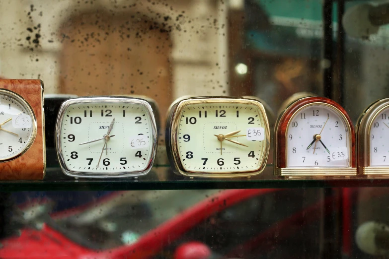 many small clocks lined up on a glass counter