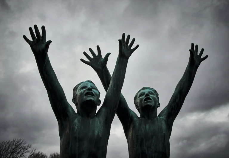 a pair of statues that are in front of a cloudy sky