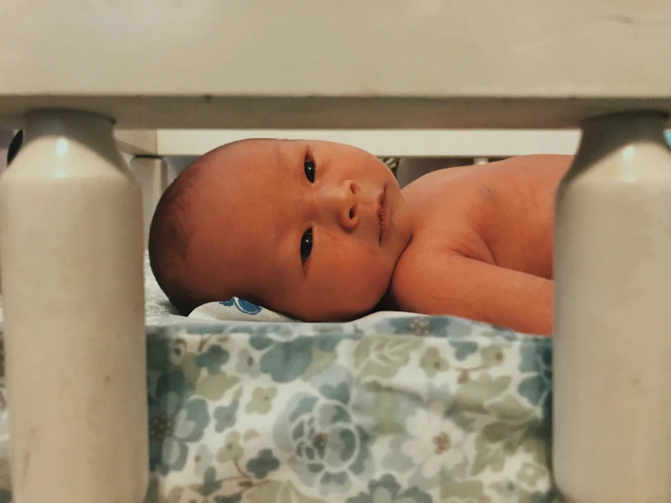 baby on back of crib surrounded by metal post supports