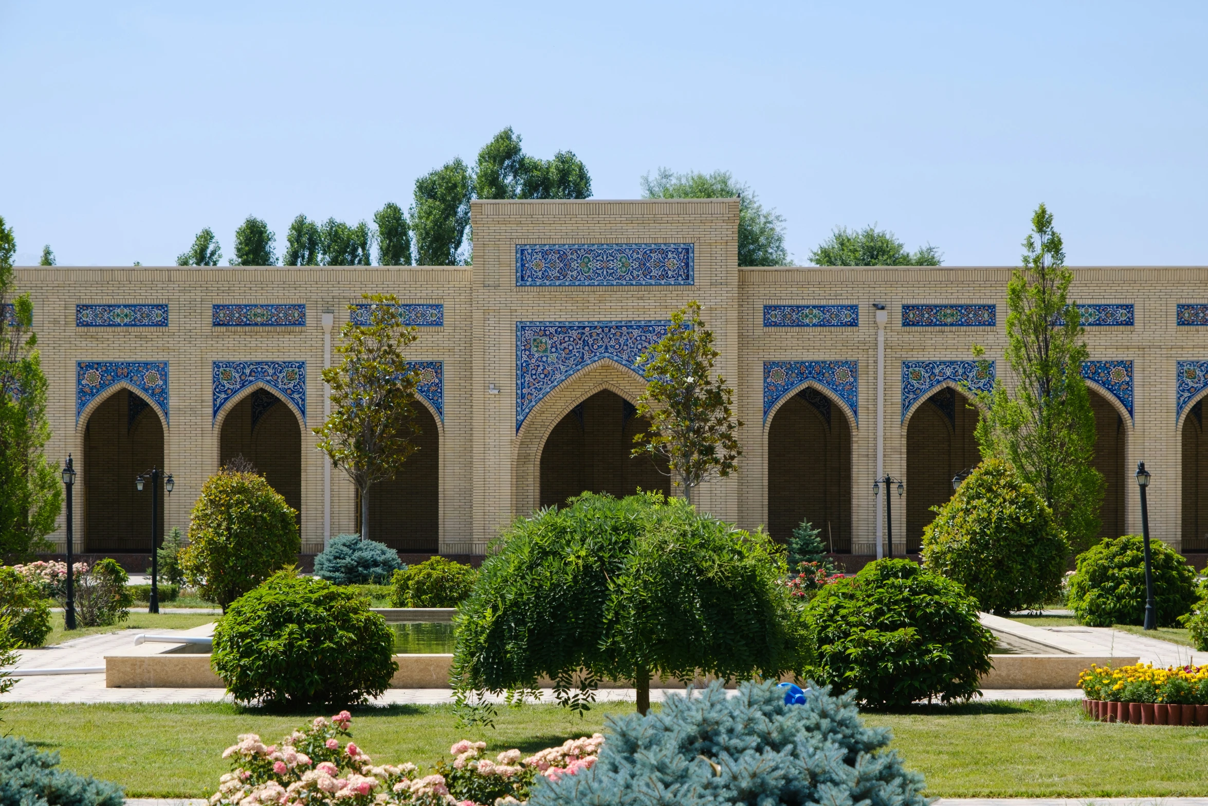 a blue building is behind a garden of flowers and trees