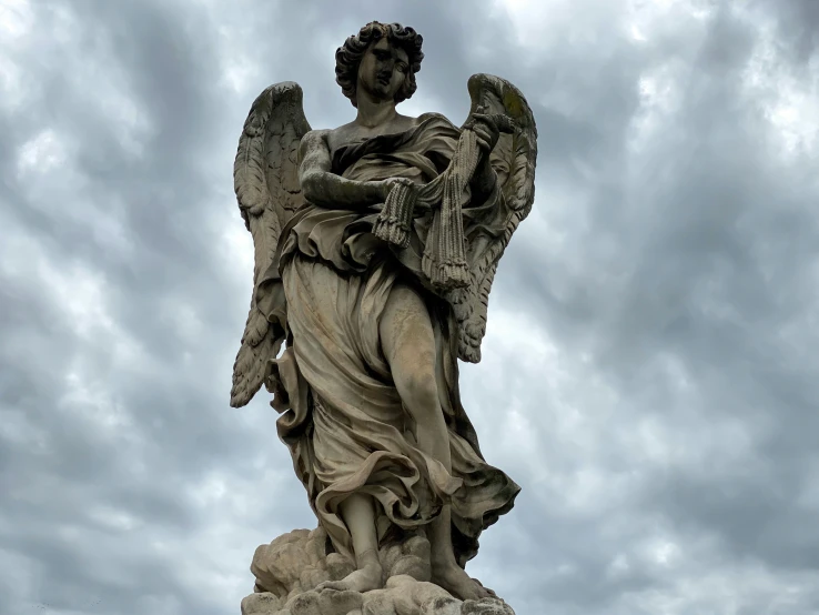 the angel statue is against a grey sky