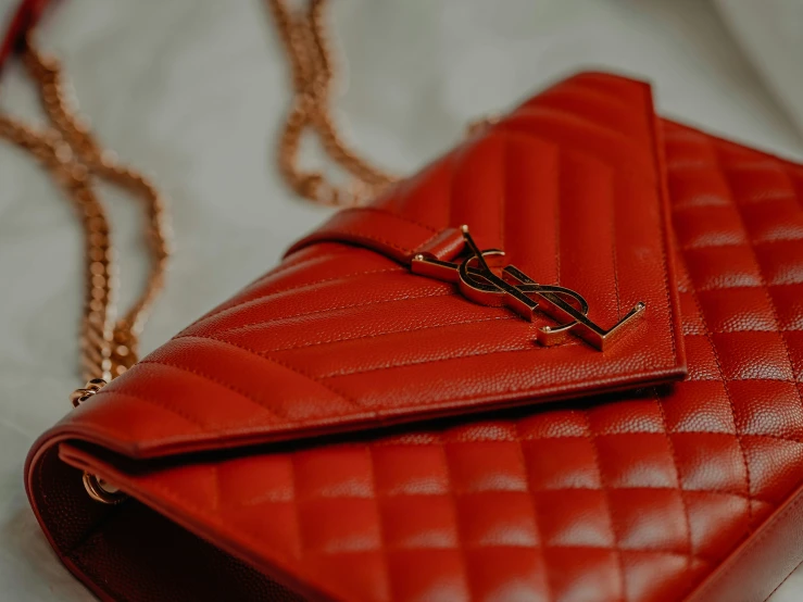 an orange red quilted leather purse on white table cloth