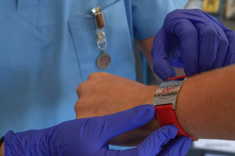 hands with purple gloves are fixing a wrist watch