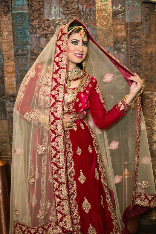 a woman in a red and gold wedding dress standing next to a wall