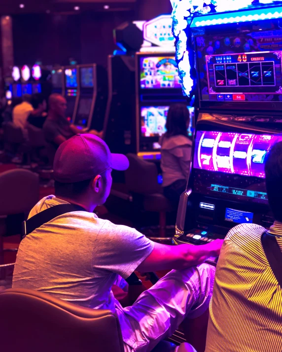 two men sit next to each other in front of slot machines