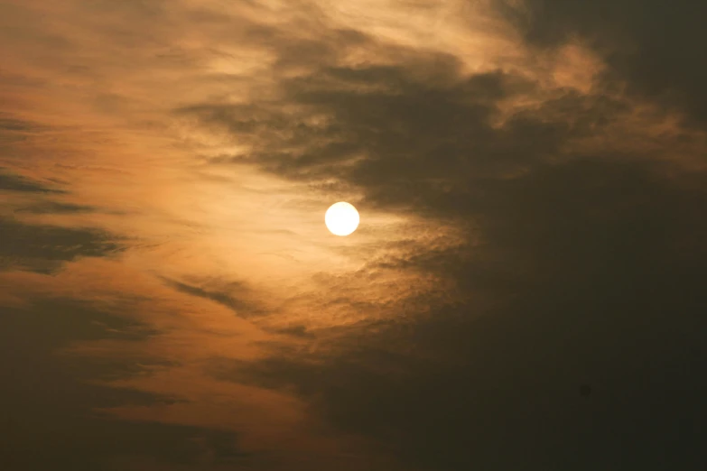 a yellow sun is seen above a cloud - filled sky