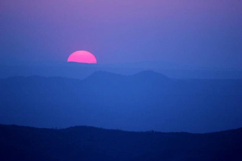 the sun is setting in the distance over mountains