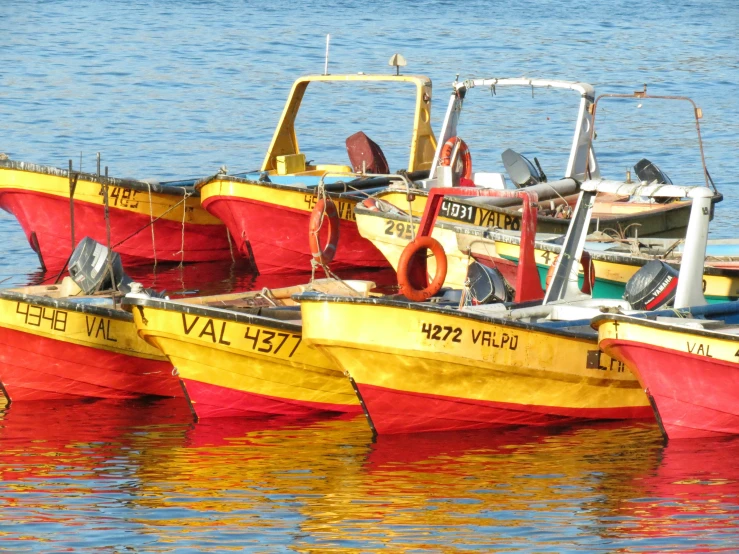three yellow red and black boats floating on top of water