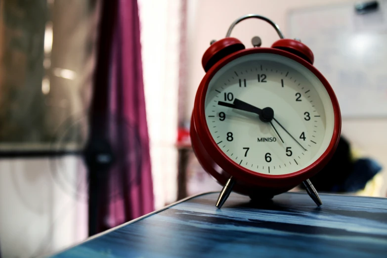 an alarm clock is red in color on the table