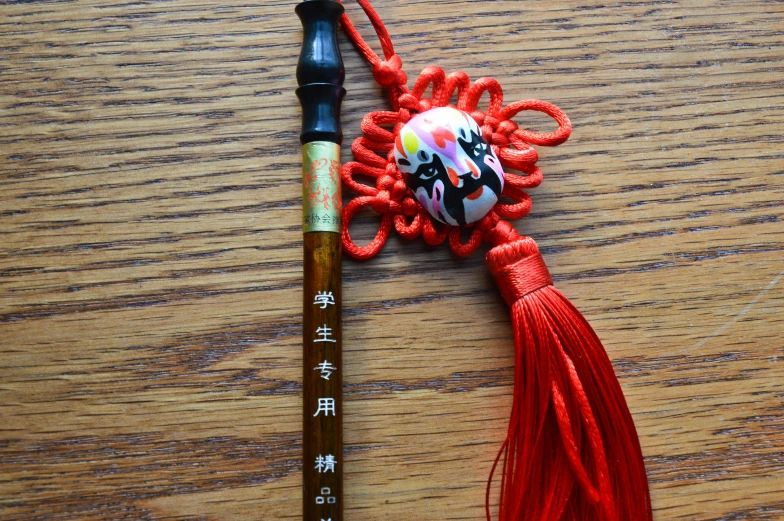 an oriental string is laying next to a wooden pencil