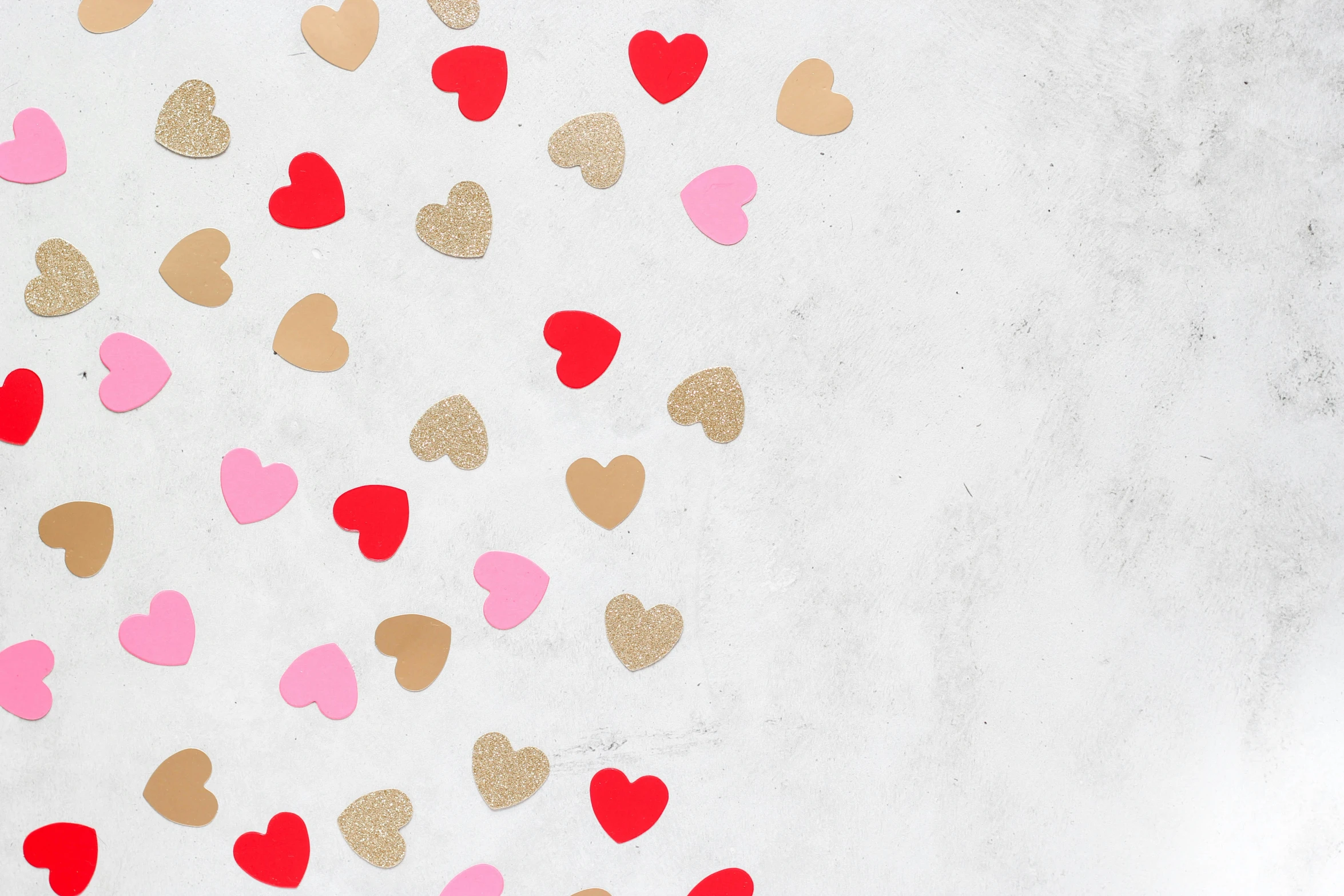 a valentine's day background with pink, gold and red hearts falling in the air