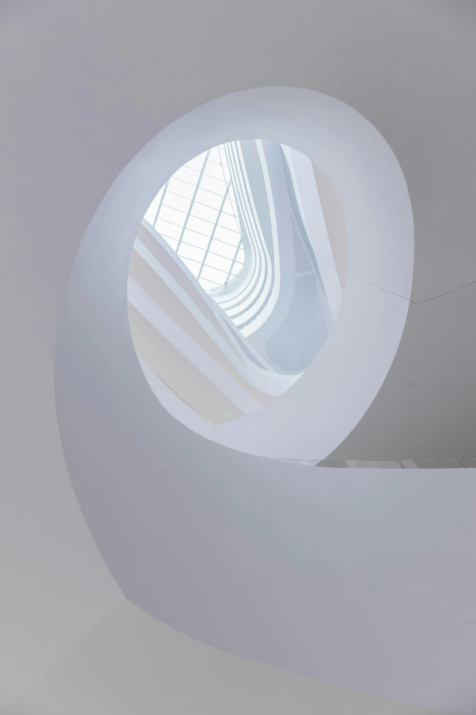 a round window shines through a very white room