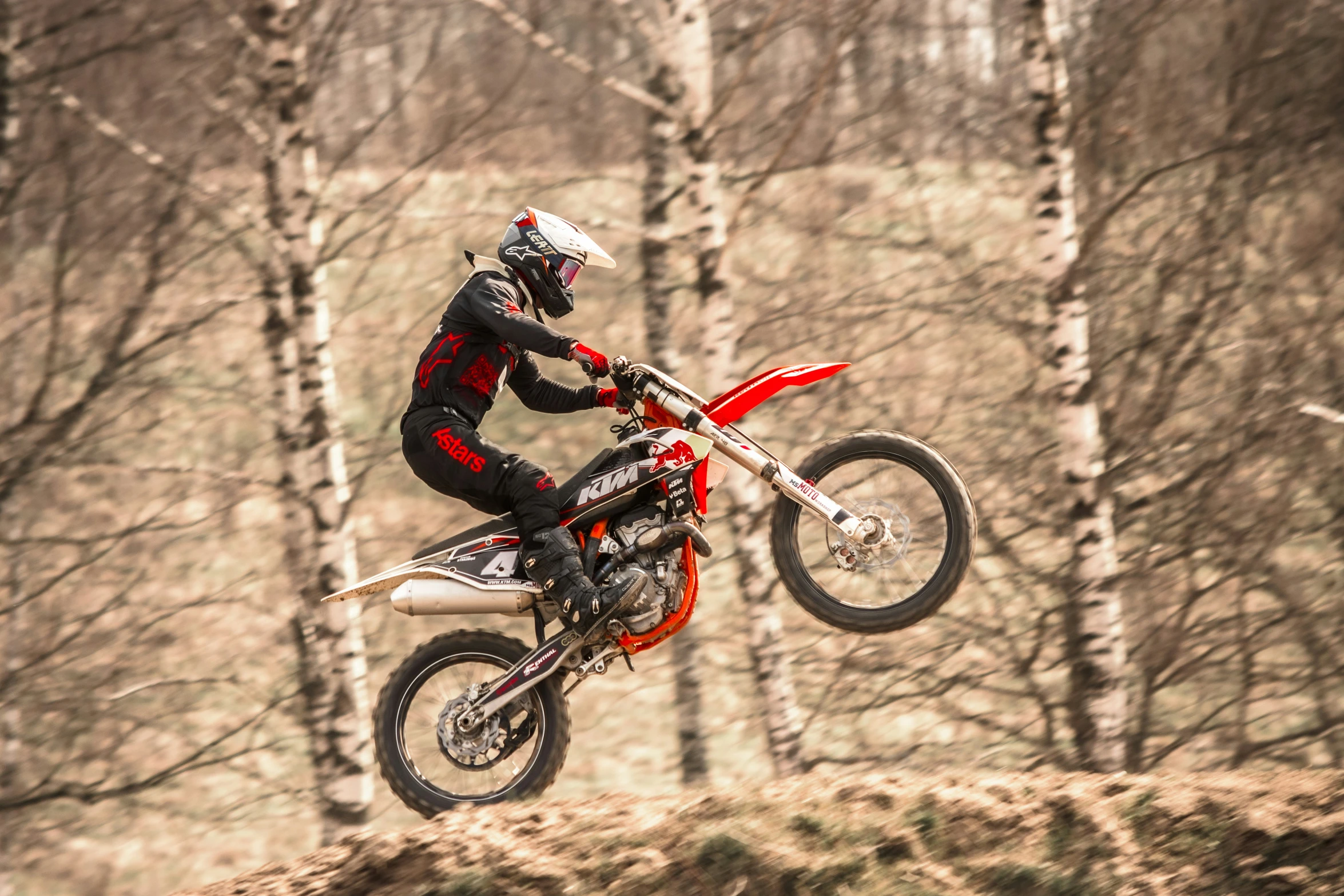 a man riding a dirt bike across a forest