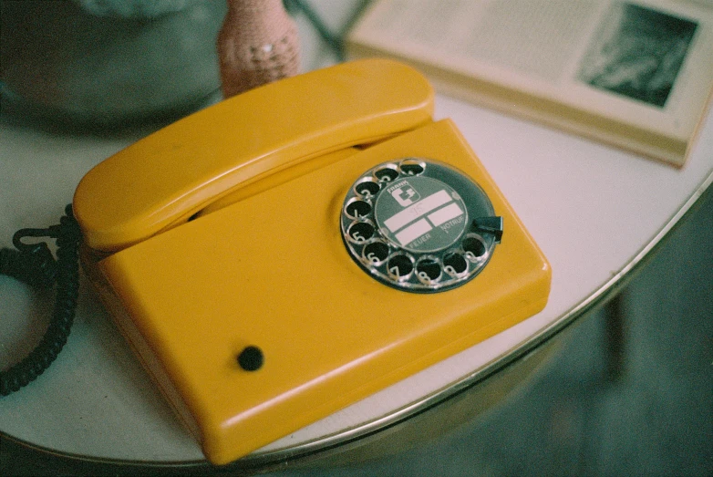 a yellow telephone and two small pographs are on a table