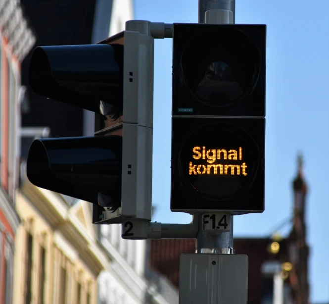 a traffic light next to a building with a signal kommni sign on it