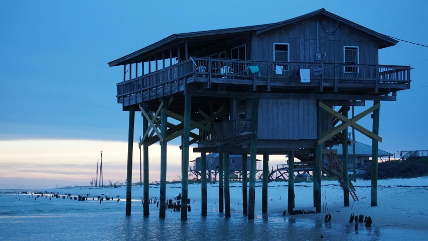 people walk around a pier with a large house on the side