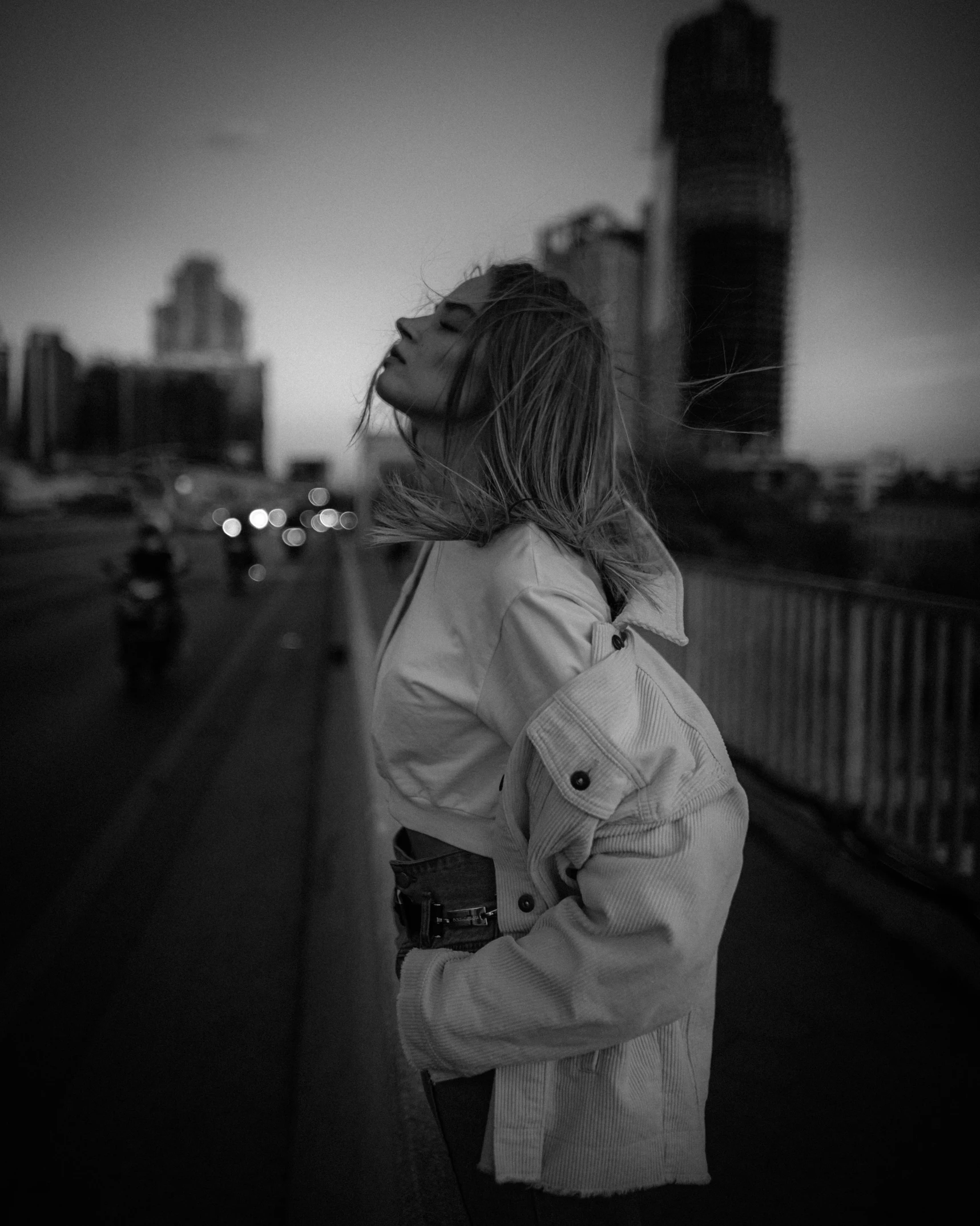 the woman is standing on the bridge in the city