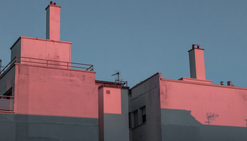 the front of an apartment building with two tall chimneys