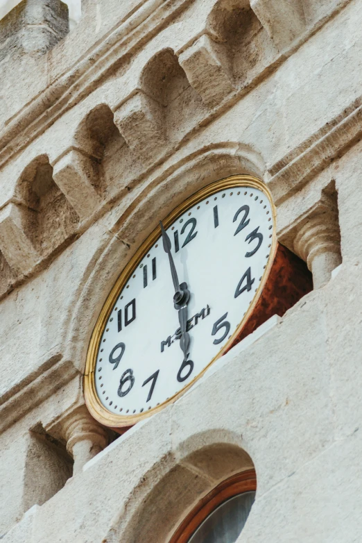 an analog clock is attached to the side of a brick building