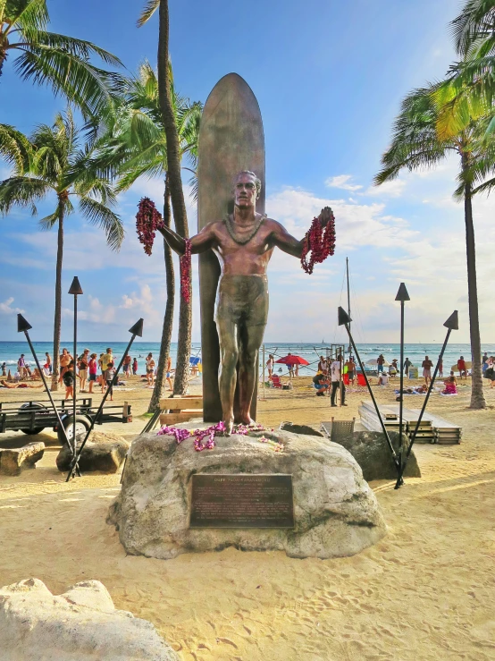 a statue of a man stands in front of the beach