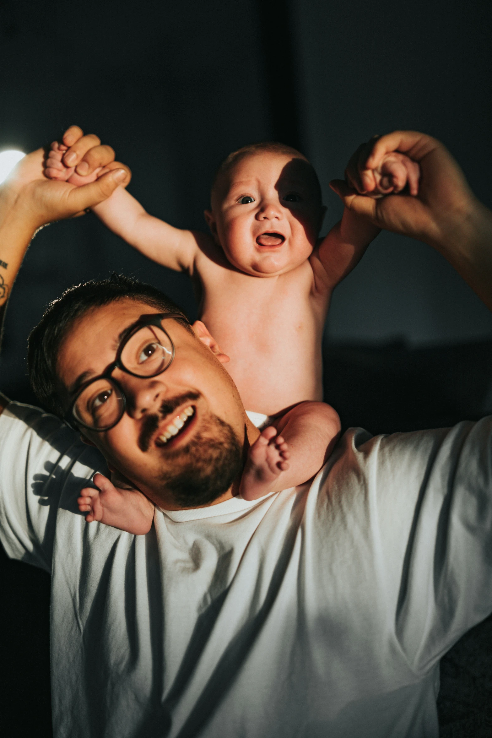 a man with glasses holding a baby up to his ear