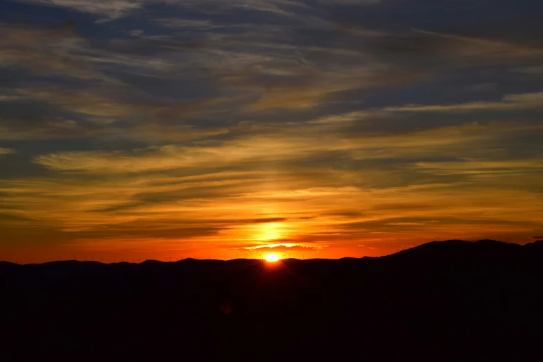 the sun is setting with clouds in the sky