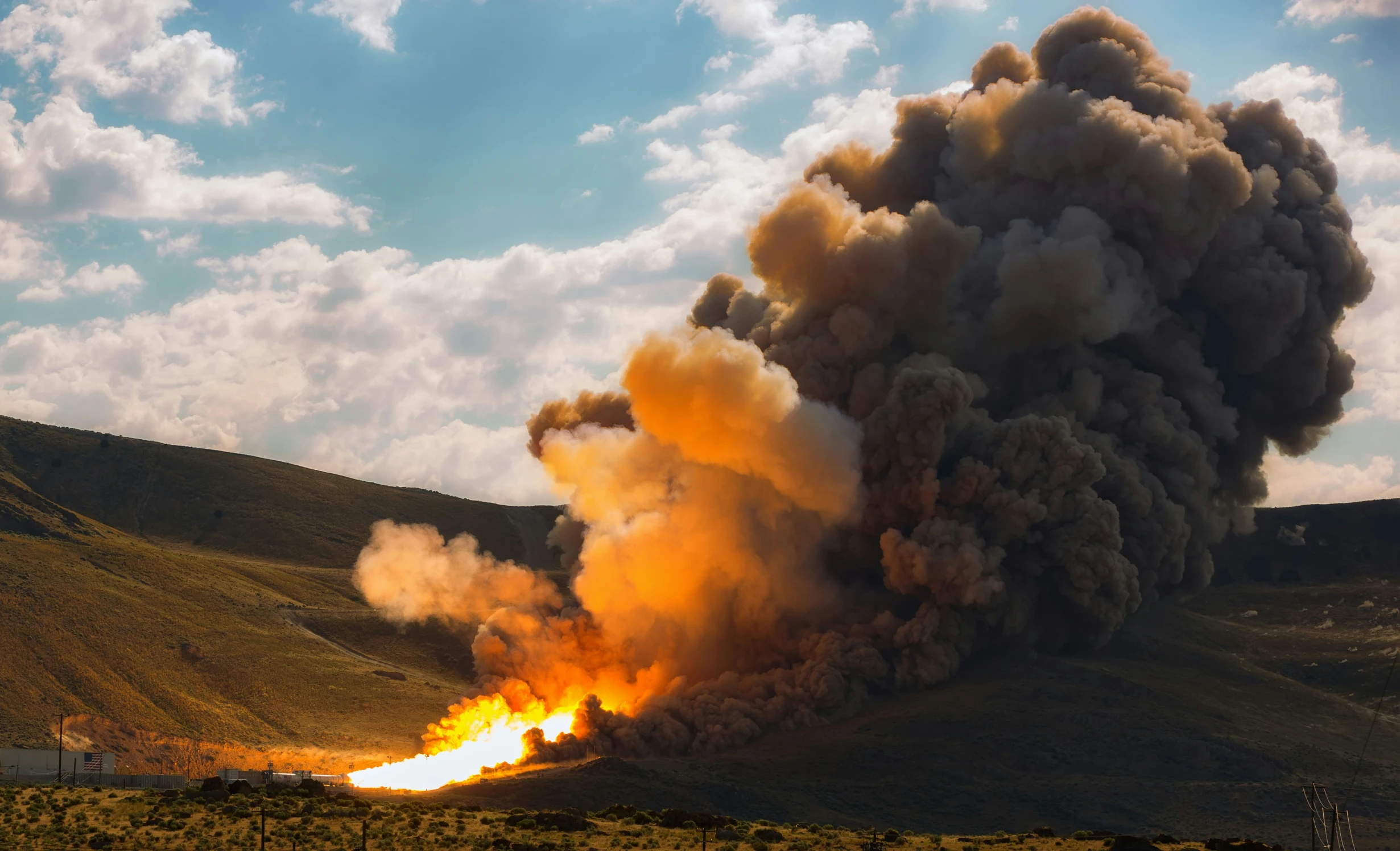 an enormous plume of smoke billows from a mountain