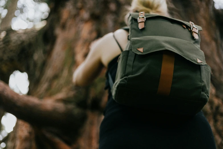 there is a woman wearing a green backpack standing in the trees