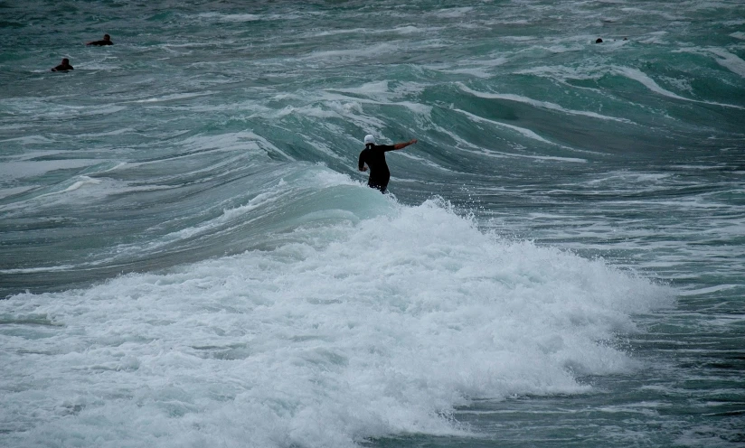 surfer in a black wet suit surfing on a wave