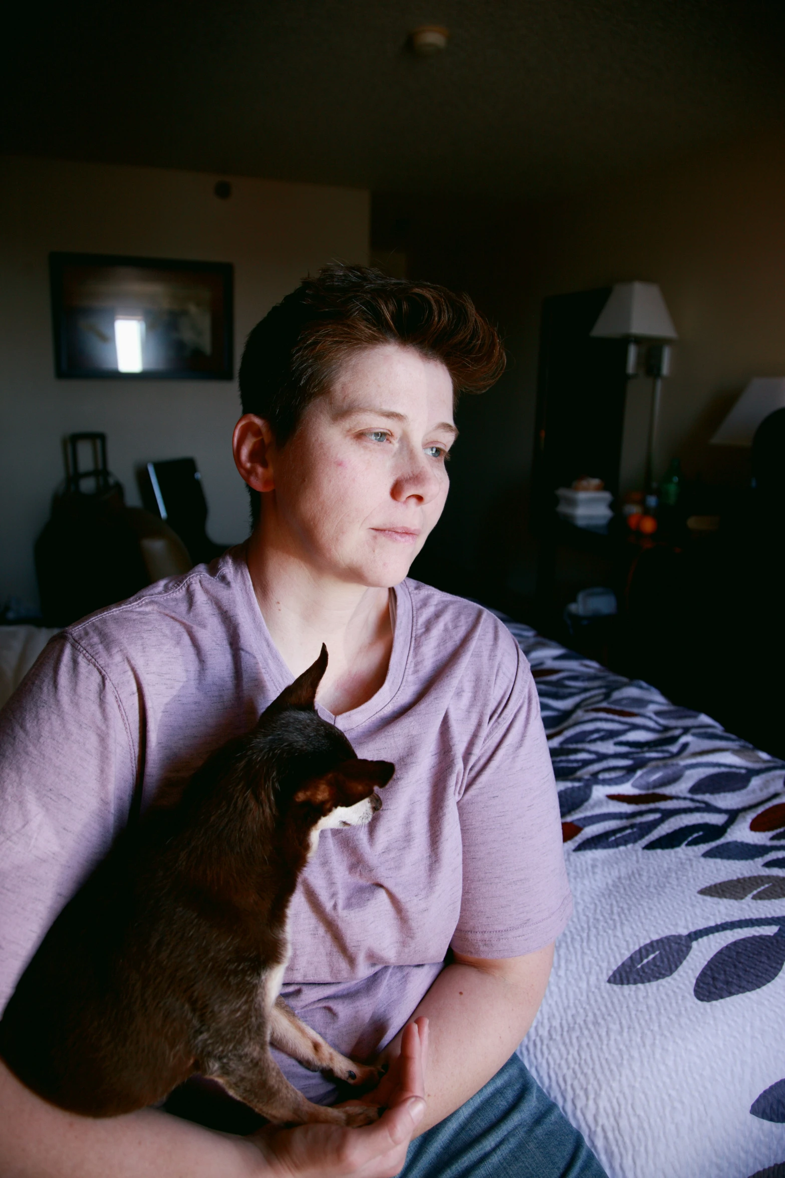 a woman sitting on a bed with her dog