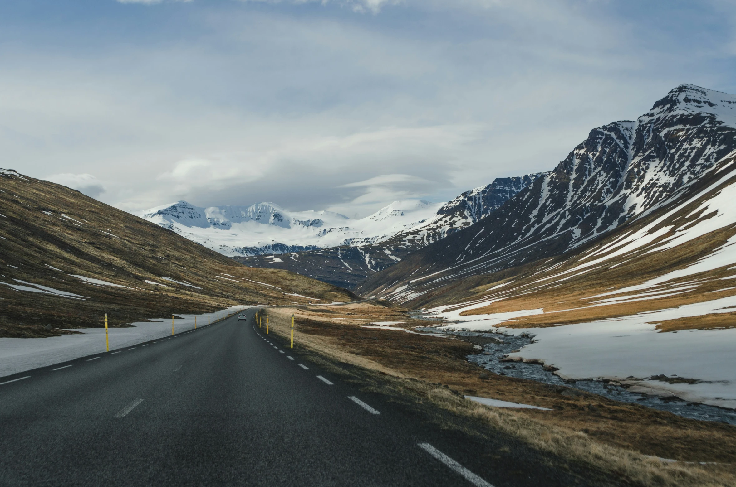 a wide open highway with snow covered mountains in the background