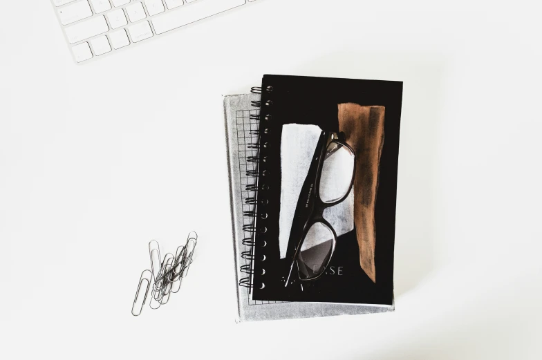 a notebook with sunglasses and pen on a desk