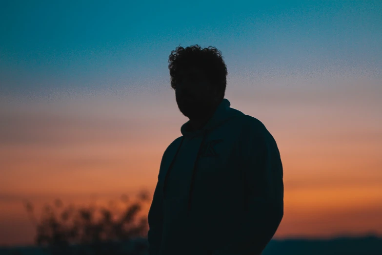 a man standing up at sunset with a bird flying in the sky