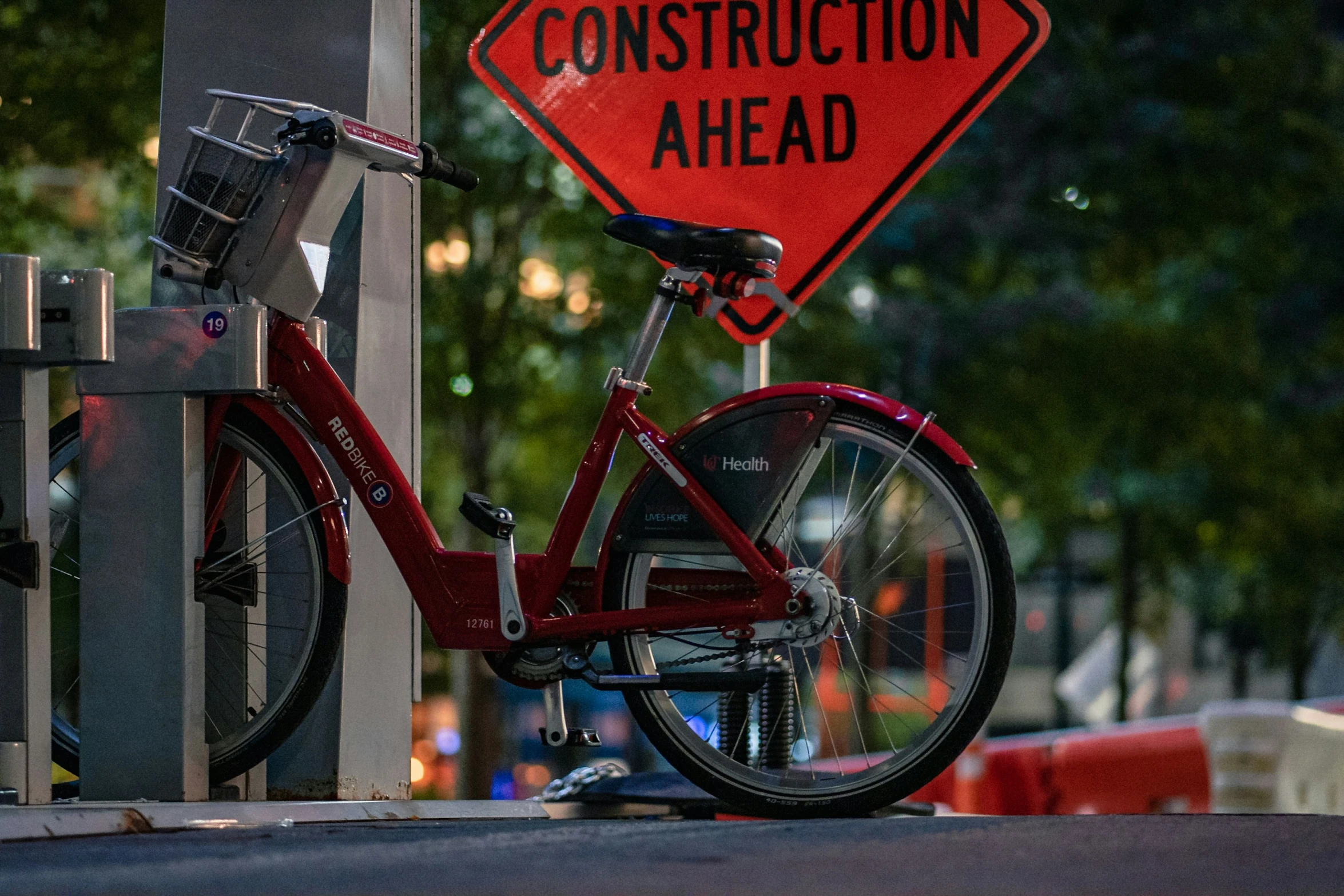 a bicycle parked under a construction sign near a parking structure