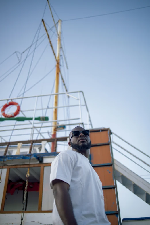 a person standing next to a boat and wearing sunglasses