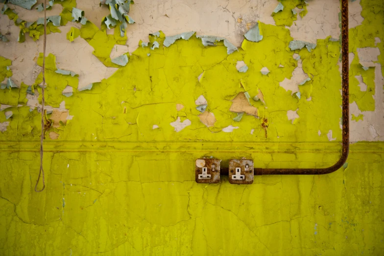 rusted metal pipes are next to a yellow wall
