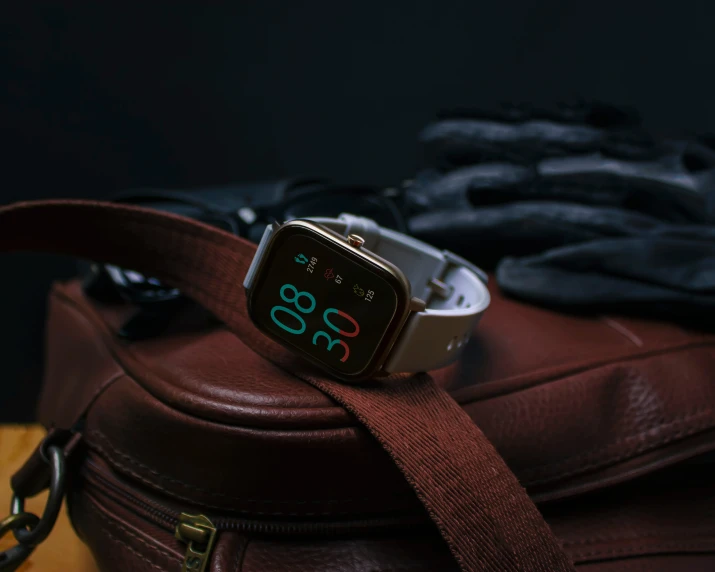 an electronic clock with roman numerals displayed on top of a suitcase