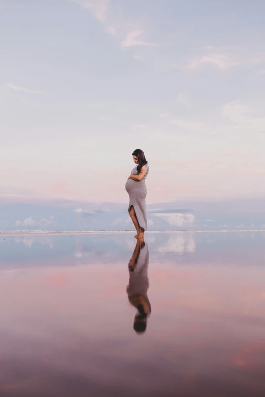 woman in dress standing on a beach at sunset