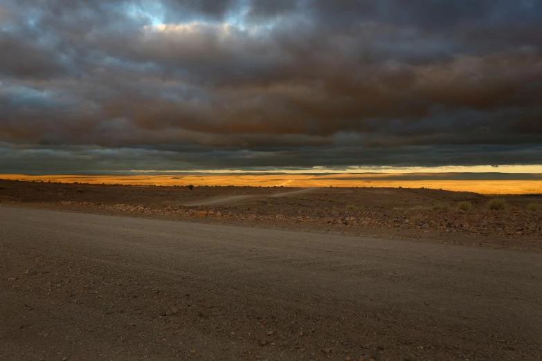 a cloudy day in the desert with only a bus or vehicle parked near the road