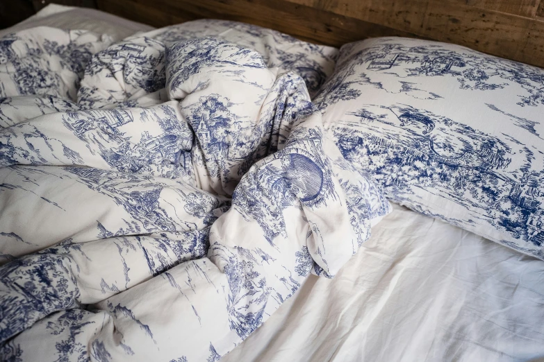 a bed with blue and white pillows is made in a messy bed