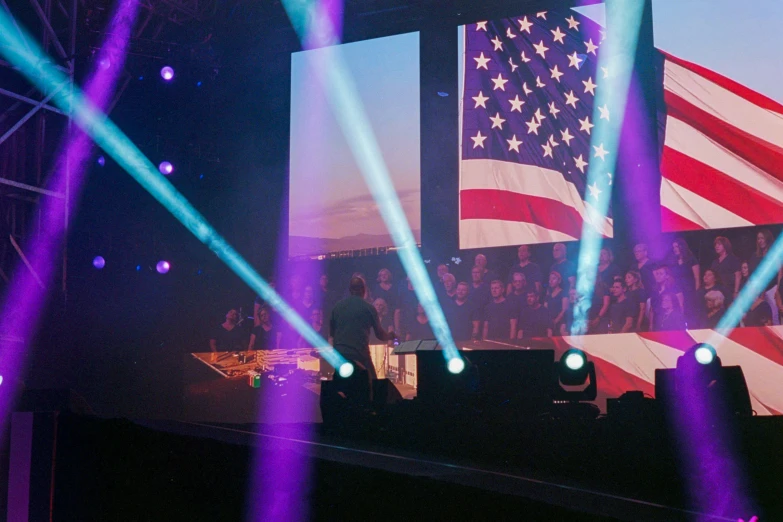 stage lights show large american flag, with blue and white flags