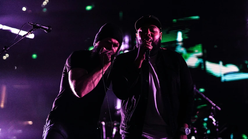 two men stand on a stage in front of lights