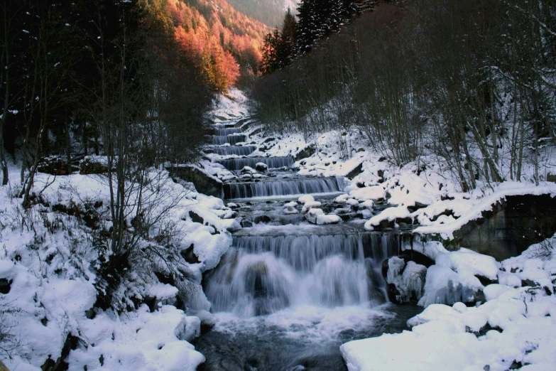 a small waterfall with snow on it is seen from the ground