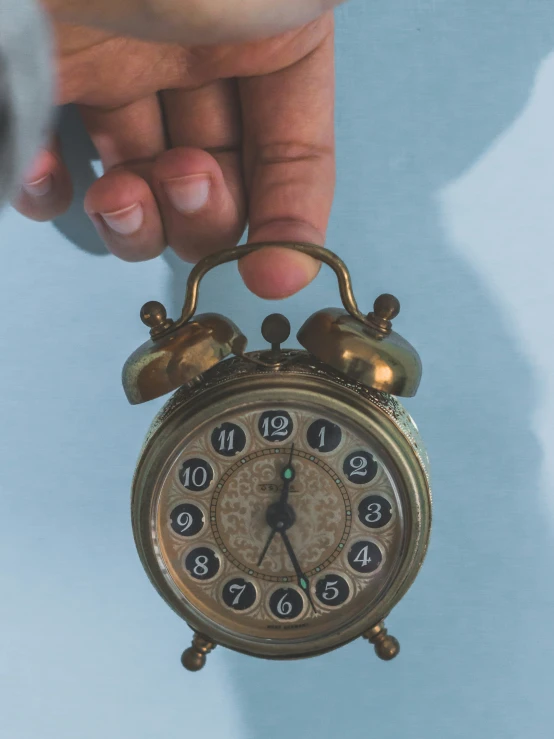 an old antique alarm clock being held by a person