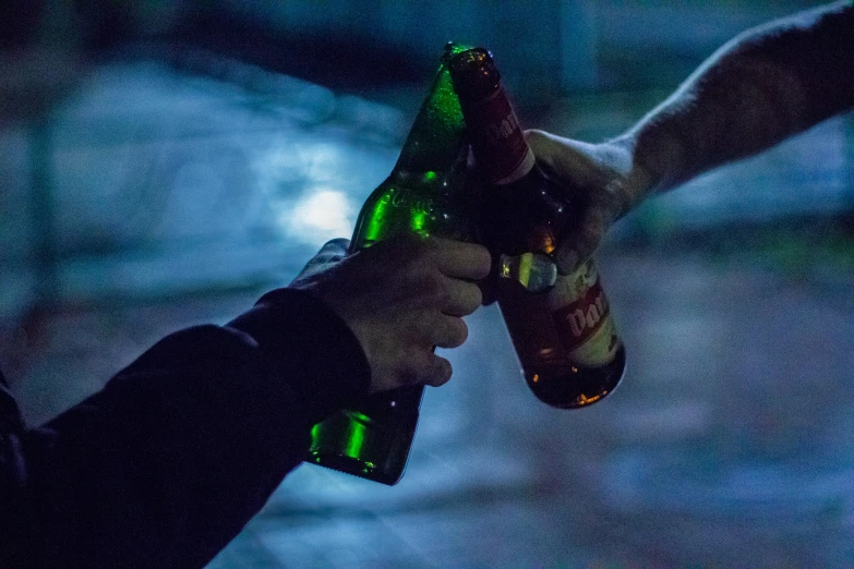 a person holding a beer bottle with two other hands