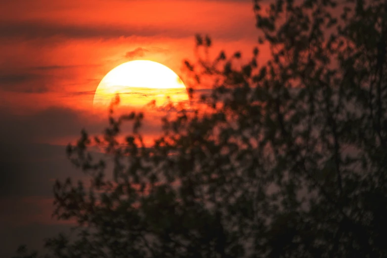 the sun set is seen through a dense layer of clouds