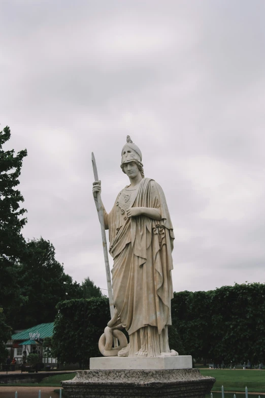 statue of the person holding a sword near a bunch of trees