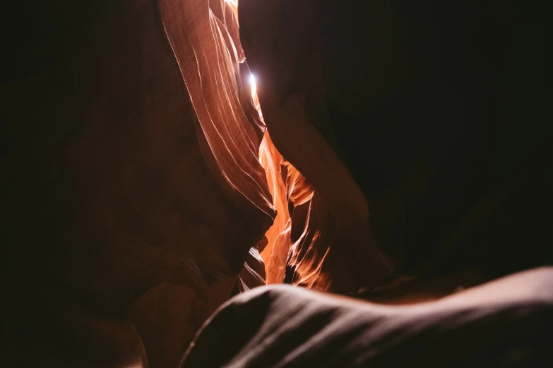 a narrow cliff with people below and light at the base